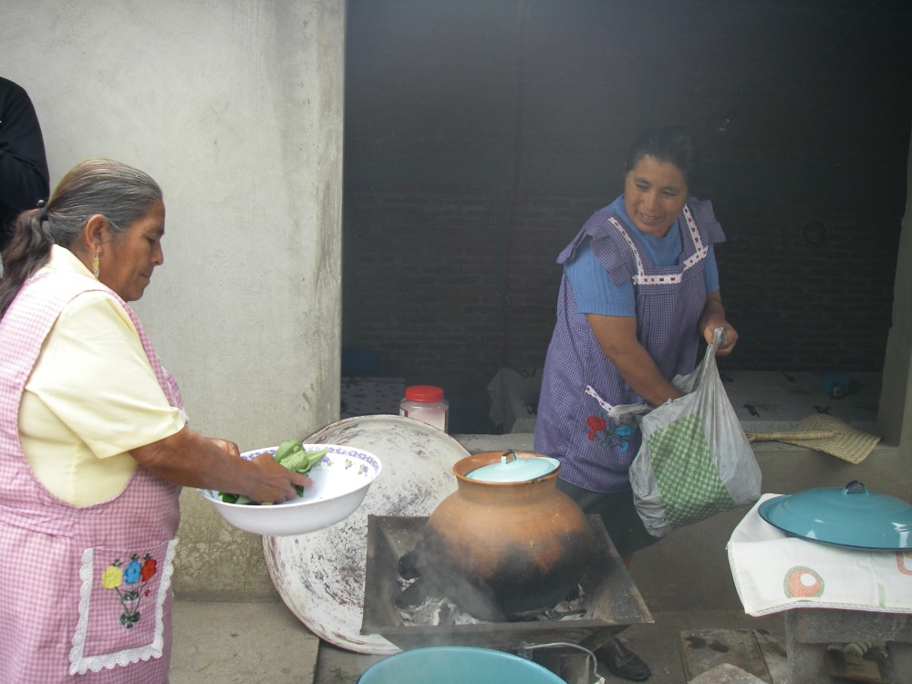 Zwei Frauen kochen im Hof eines Hauses.