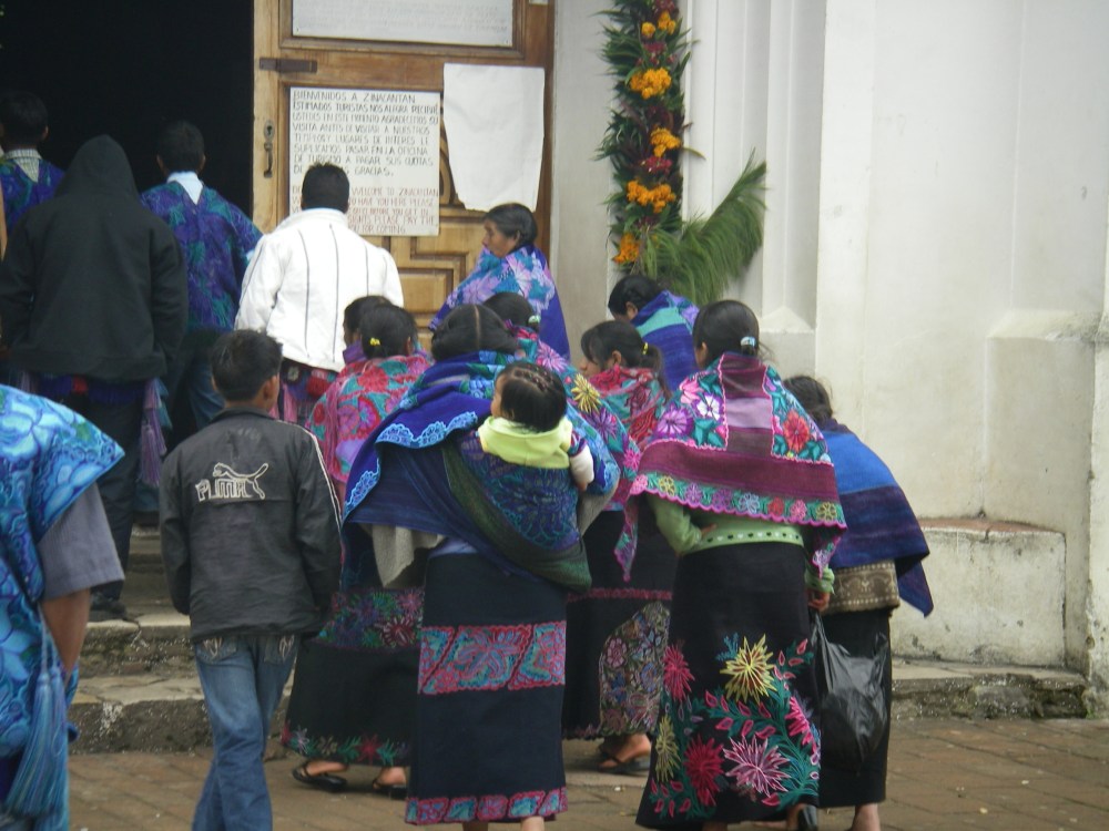 Frauen mit bunten Schultertüchern gehen in die Kirche.