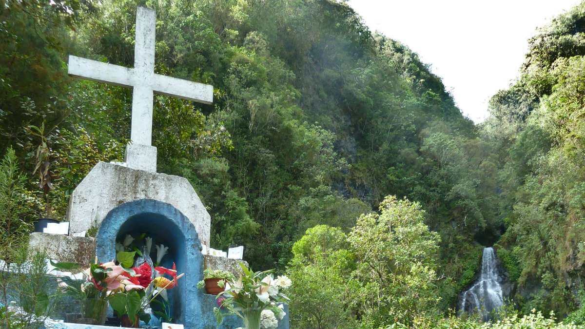 Weißer Schrein mit Kreuz im Wald.