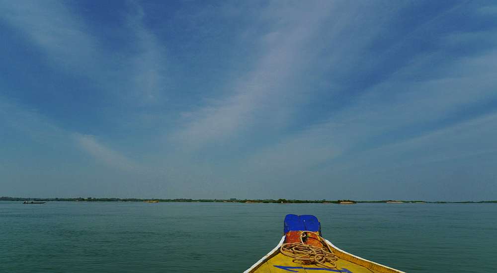 Ein Boot segelt auf ruhigen Gewässern unter einem klaren blauen Himmel, am Horizont ist eine entfernte Küstenlinie zu sehen und fängt einen idyllischen Moment ein, der perfekt für die Fotoparade ist.