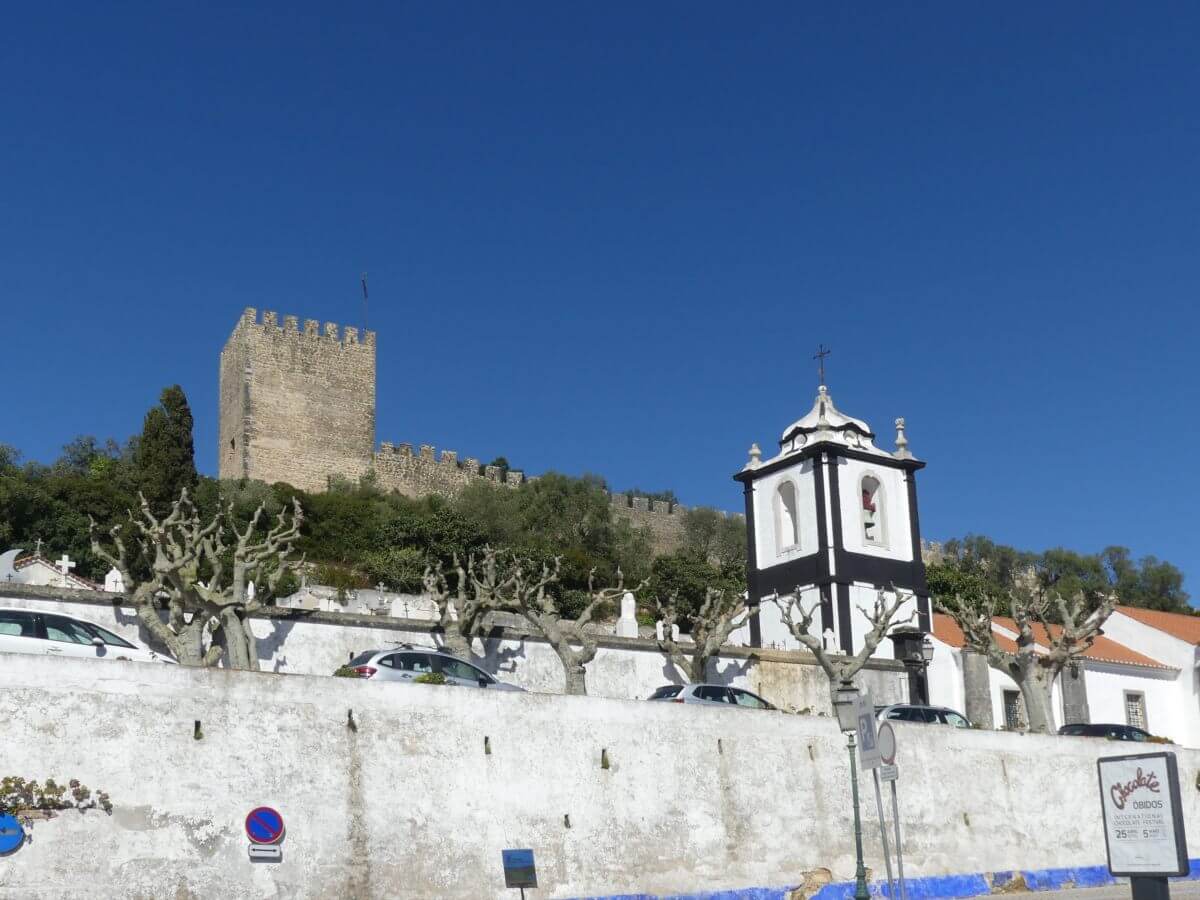 REchteckiger Turm der Stadtmauer, im Vordergrund eine Kirche.