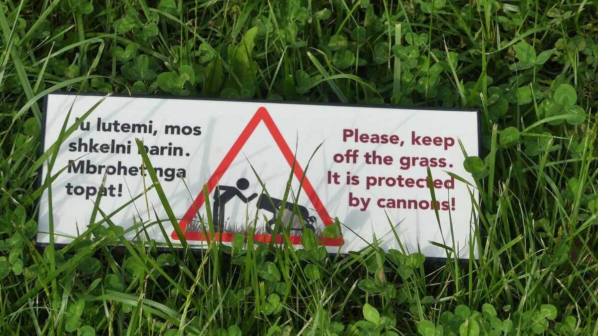 Schild mit Text Please keep off the grass. It is protected by cannons.