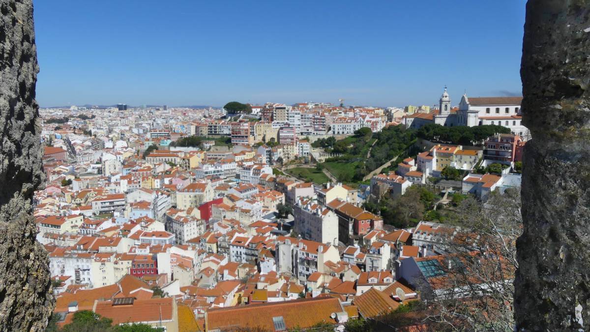 Blick durch die Zinnen der Burgmauer auf die Dächer von Lissabon.