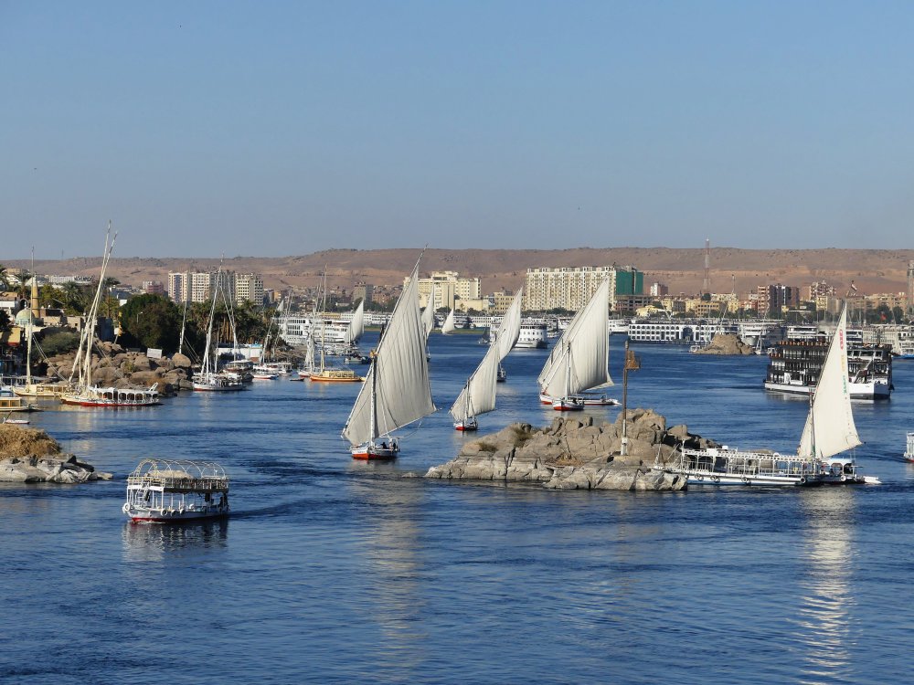 Mehrere Feluken segeln zwischen Felsklippen auf dem Nil.