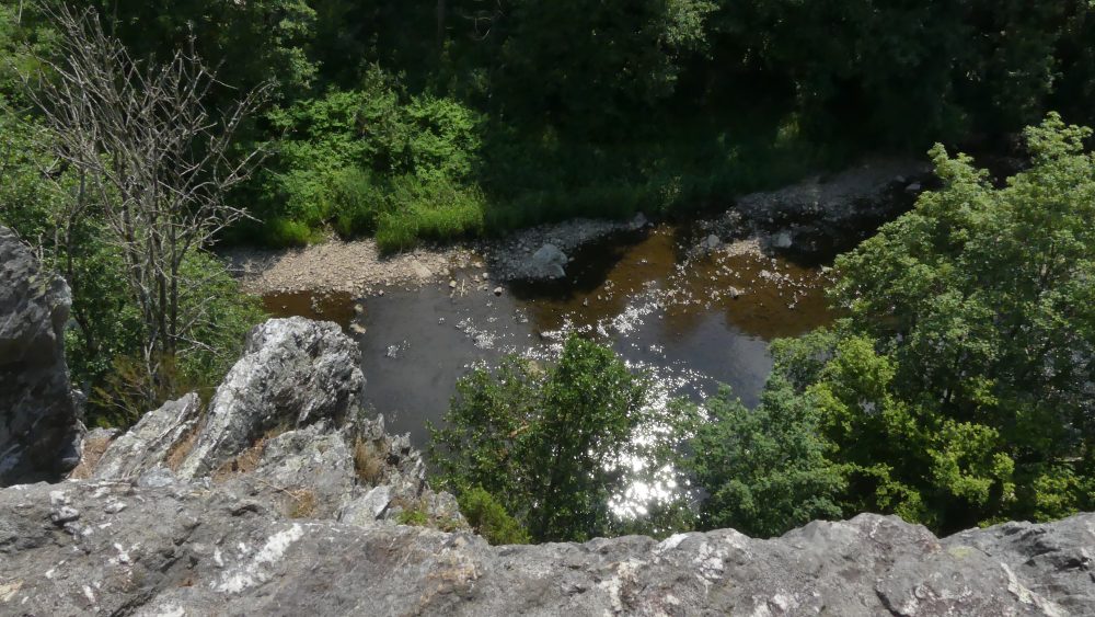 Blick an der Felswand hinunter bis zum Fluss.