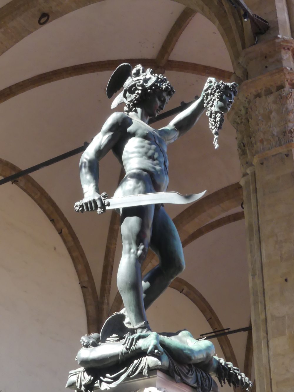 Bronzestatue hält abgeschlagenen Kopf hoch.