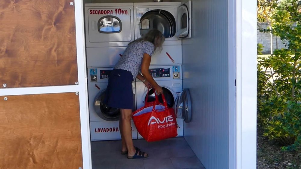 Gina bringt Wäsche zur Waschmaschine auf dem Campingplatz.