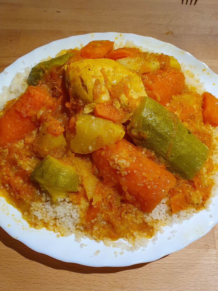 Teller mit Couscous, Möhren, Zucchini und Fleisch.