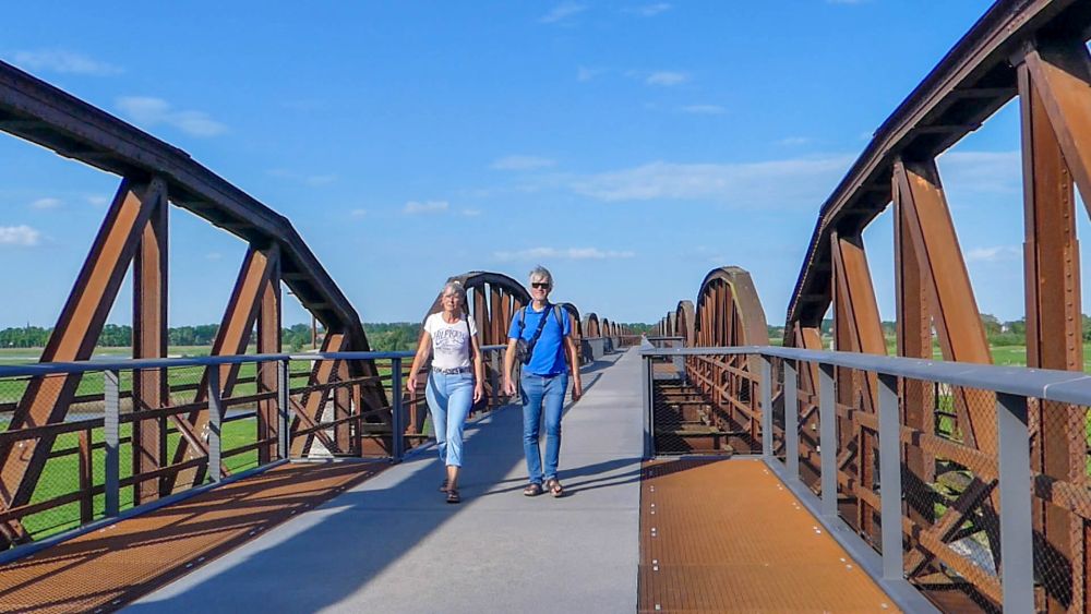 Gina und Marcus gehen über Steg auf der Eisenbahnbrücke.