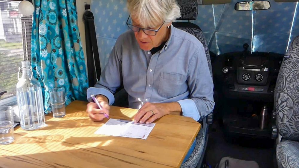 Marcus sitzt am Tisch mit einem Blatt Papier vor sich und einem Stift in der Hand.