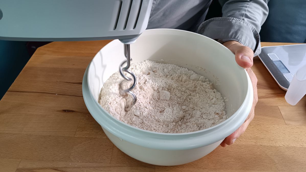 Die Zutaten in der Schüssel werden mit dem Handmixer geknetet.