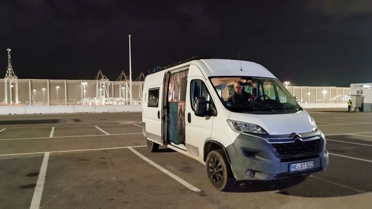 Wohnmobil steht in der Dunkelheit auf einem großen Parkplatz.