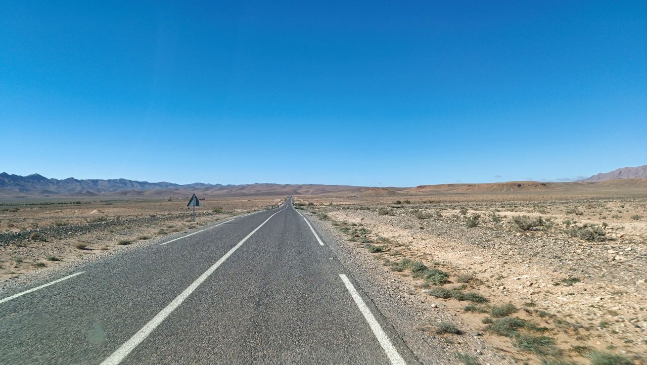 Straße führt durch eine flache Wüstenlandschaft.